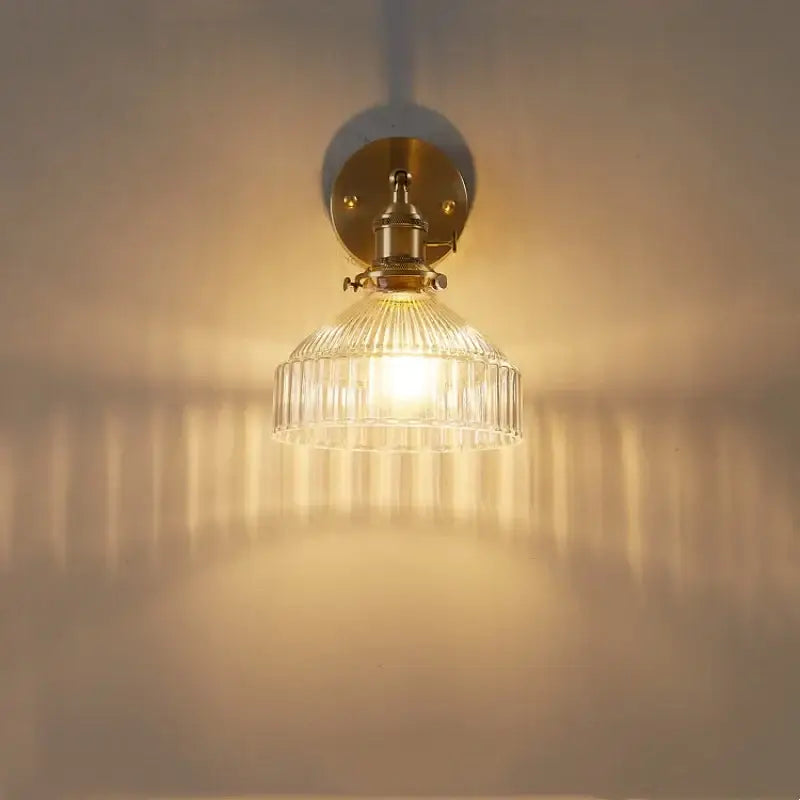 Vintage brass wall lamp with clear glass shade and pull chain switch providing warm light for bedroom use