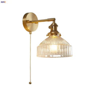 Vintage brass wall lamp with clear ribbed glass shade and pull chain switch for bedroom lighting