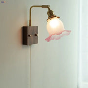 Vintage brass wall lamp with a glass pink led shade featuring ruffled edges for bedroom sconce lighting