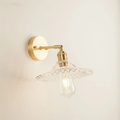 Brass-finished wall light with a clear scalloped glass led wall shade and exposed Edison bulb for bedroom use