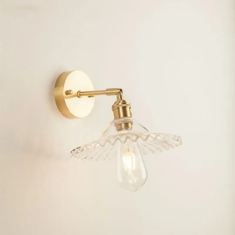 Brass-finished wall light with a clear scalloped glass led wall shade and exposed Edison bulb for bedroom use
