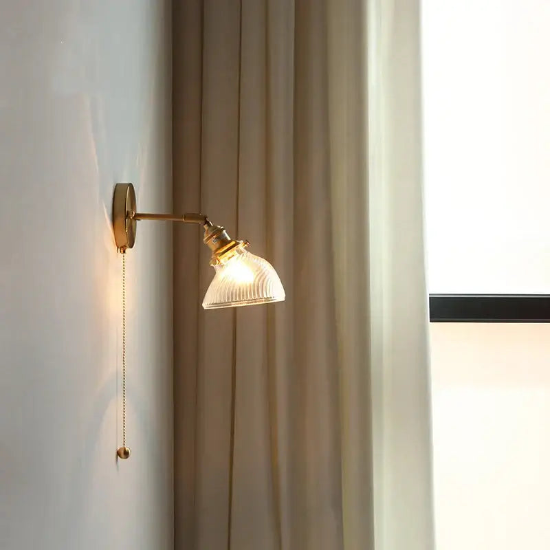 Gold-toned vintage brass led wall light with ribbed translucent glass shade and adjustable arm for bedroom use