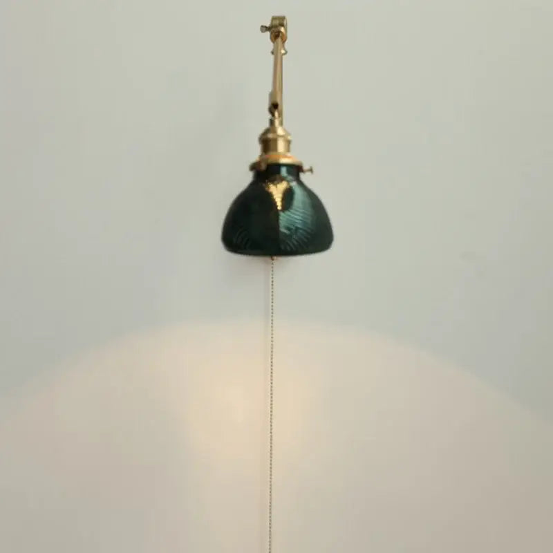 Vintage brass and green glass wall light fixture with pull-chain switch designed as a bedroom sconce light fixture
