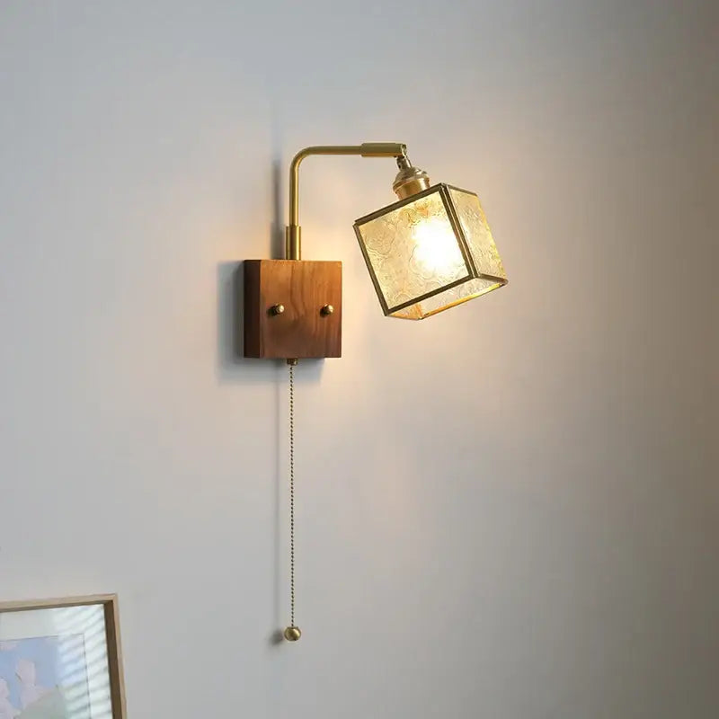 Vintage brass and walnut wall light with textured glass cube shade and pull chain switch for bedroom use