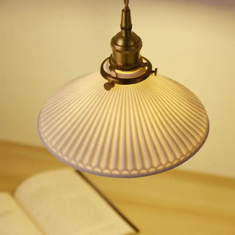 A warm-toned ribbed glass pendant light with brass-finished metal and white shade for dining rooms