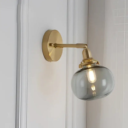 Gold-toned vintage brass led wall lamp with clear smoky glass spherical shade for bedroom sconce lighting