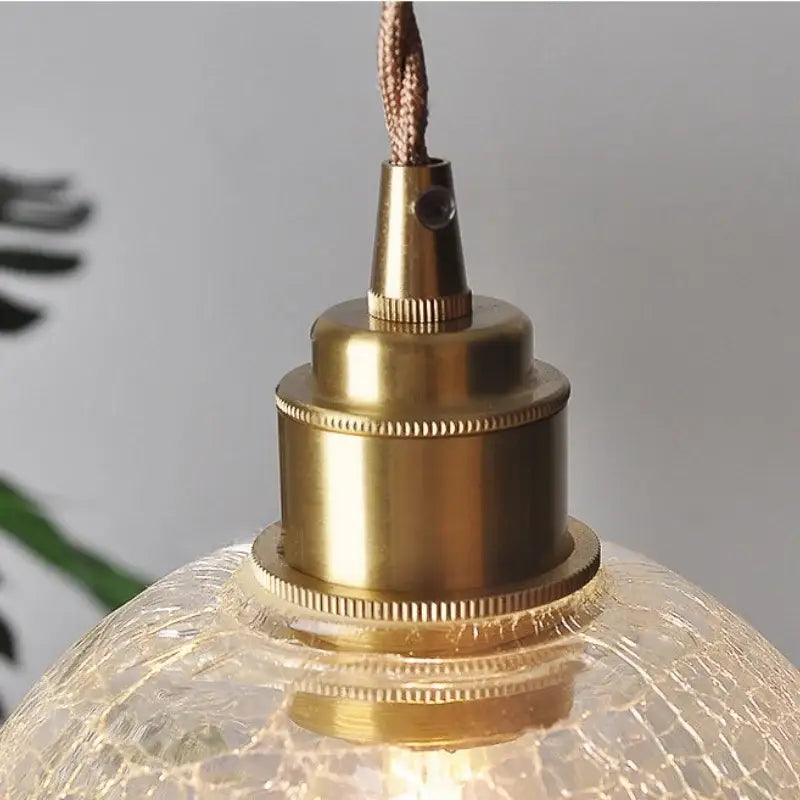 Brass-finished pendant light with a textured crackled glass globe featuring decorbites glass globe led design