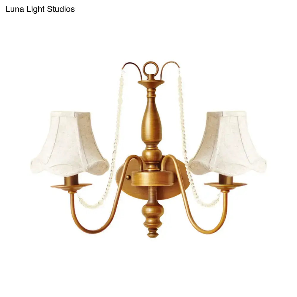 Antique brass two-light wall sconce with cream fabric shades and vintage crystal bead chains for bedroom candle light