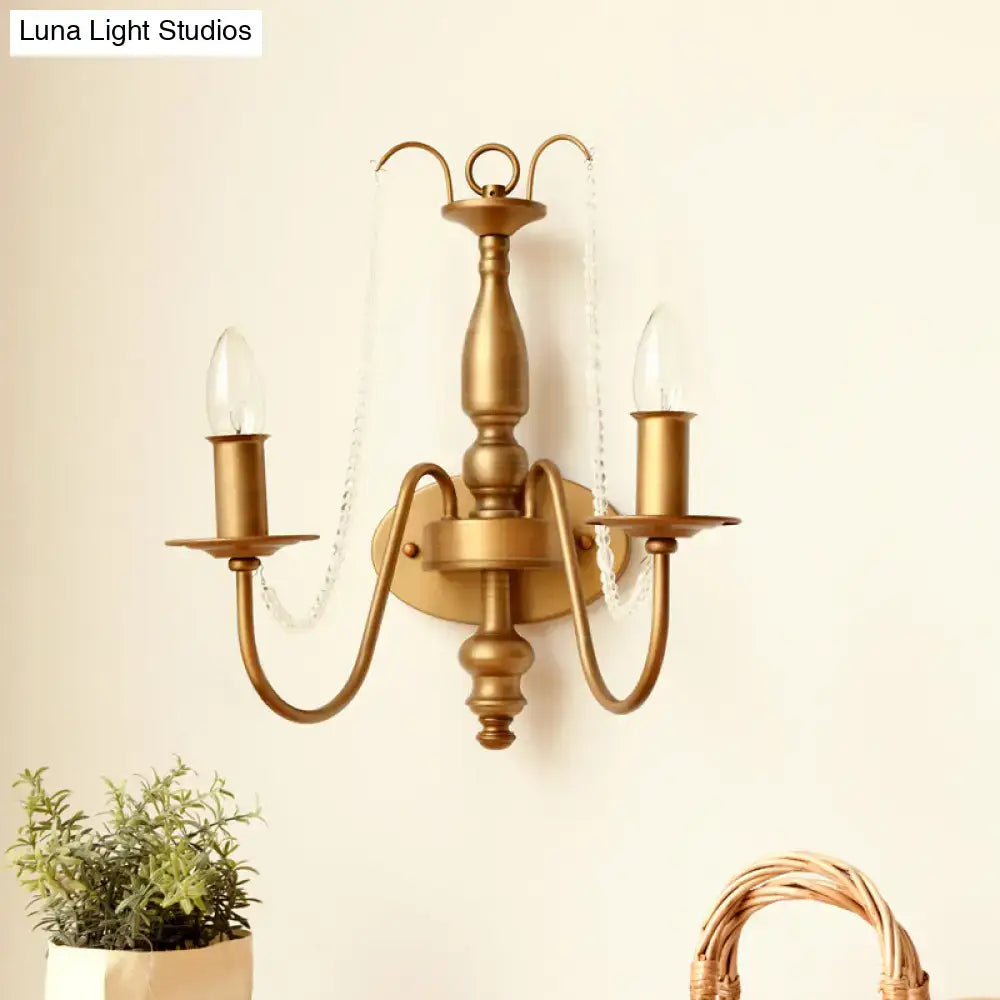 Antique brass two-light wall sconce with clear glass candle-style bulbs and decorative crystal chains for bedroom lighting