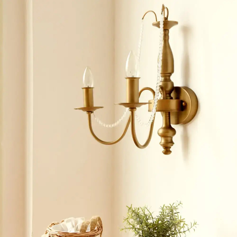 Antique brass wall sconce with three candle-style arms and delicate crystal bead chain for vintage bedroom lighting