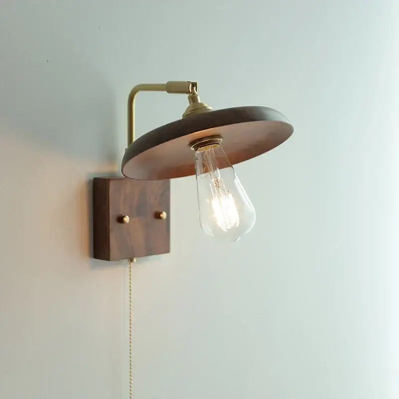 A warm brass-finished wall light sconce with dark wood shade and exposed Edison bulb for bedroom decorbites copper lighting