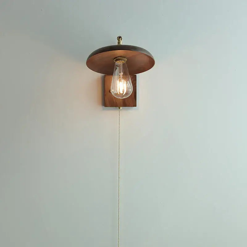 A warm-toned vintage brass and dark wood wall light sconce with exposed filament bulb for bedroom decorbites copper