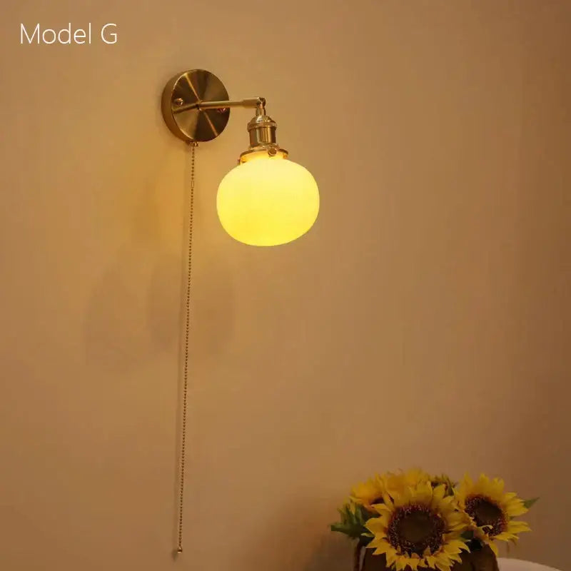 Brass-finished decorbites ceramic sconce lamp with frosted glass globe and pull chain for bedroom reading light