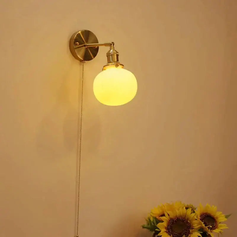 Vintage brass decorbites ceramic sconce lamp with warm yellow glass globe and adjustable arm for bedroom reading light