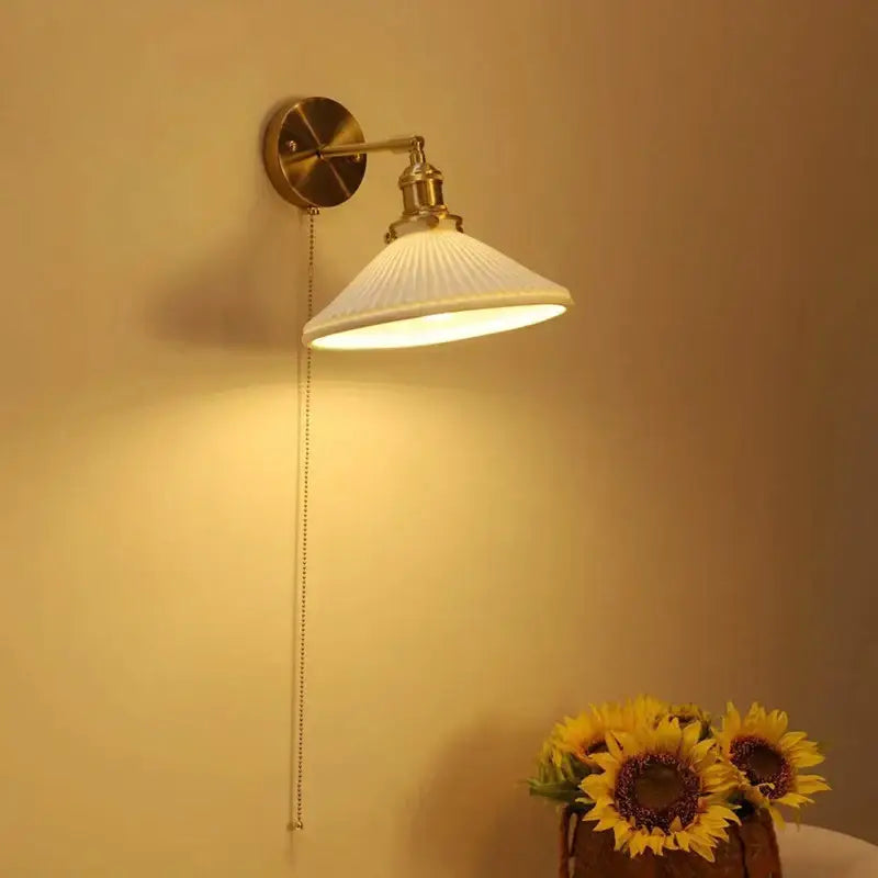 A warm-toned vintage brass decorbites ceramic sconce lamp with a white ribbed shade and adjustable arm for reading light