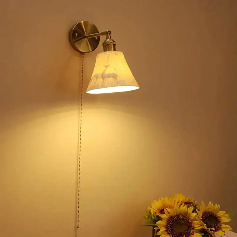 Vintage brass decorbites ceramic sconce lamp with cream fabric shade featuring subtle deer silhouette for bedroom reading light