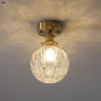 Vintage brass ceiling light with etched clear glass globe featuring intricate leaf patterns for living room use