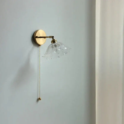 Delicate vintage brass wall light with clear petal-shaped fluted glass bedside sconce and elegant pull-chain switch