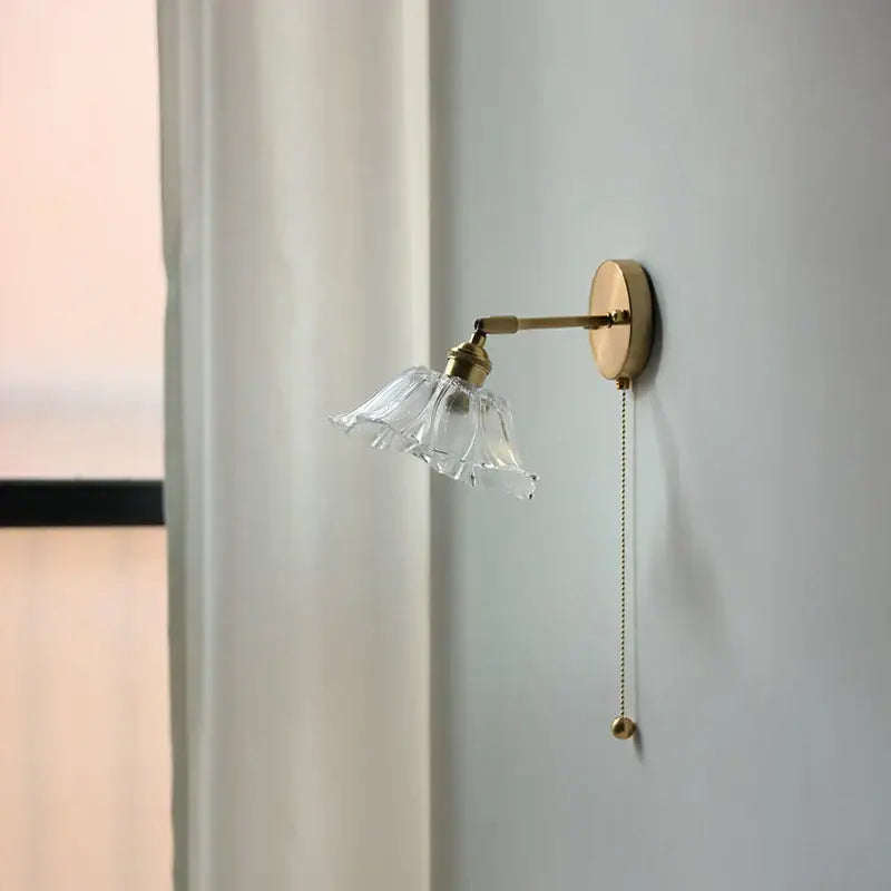Vintage brass wall light with a clear fluted glass bedside sconce and elegant pull-chain switch for bedroom decorbites