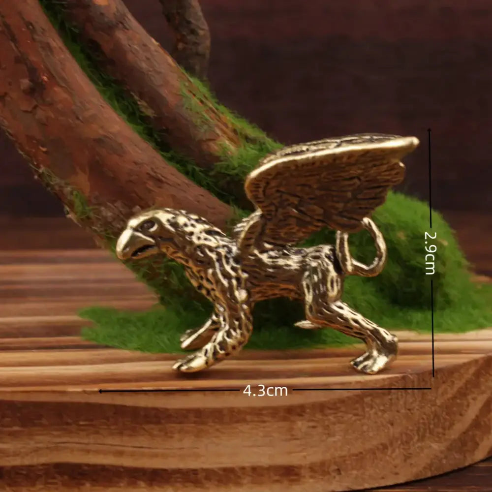 Vintage brass flying dragon sculpture featuring a golden brass griffin figurine with detailed wings on wooden surface