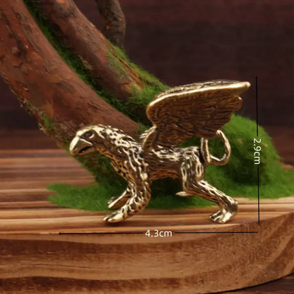 Vintage brass flying dragon sculpture featuring a golden brass griffin figurine with detailed wings on wooden surface