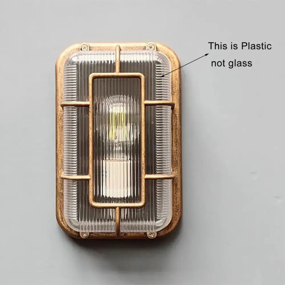 Vintage brass gas station canopy wall light with a ribbed translucent cover and metal frame for outdoor security