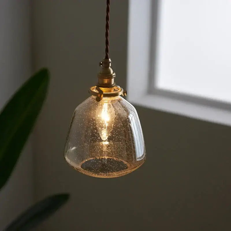 A warm-toned vintage brass glass led pendant light with textured shade and twisted cord for dining room use