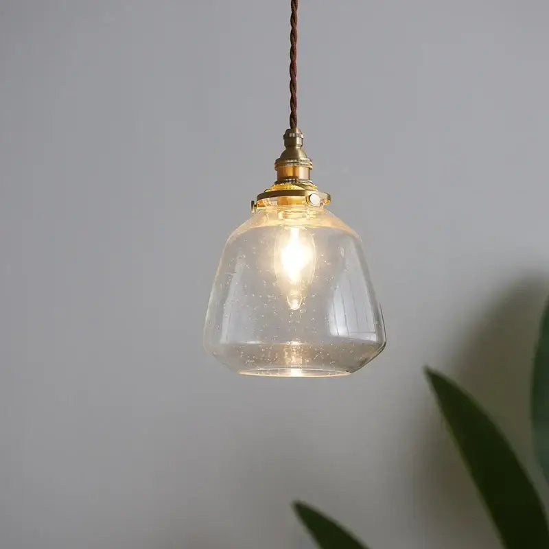 A warm-toned glass led pendant light with brass fixture and twisted brown cord for dining room use