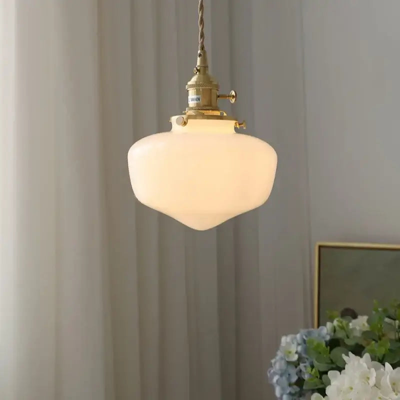 A warm glowing vintage brass glass led pendant light with frosted off-white shade for kitchen hanging lamp
