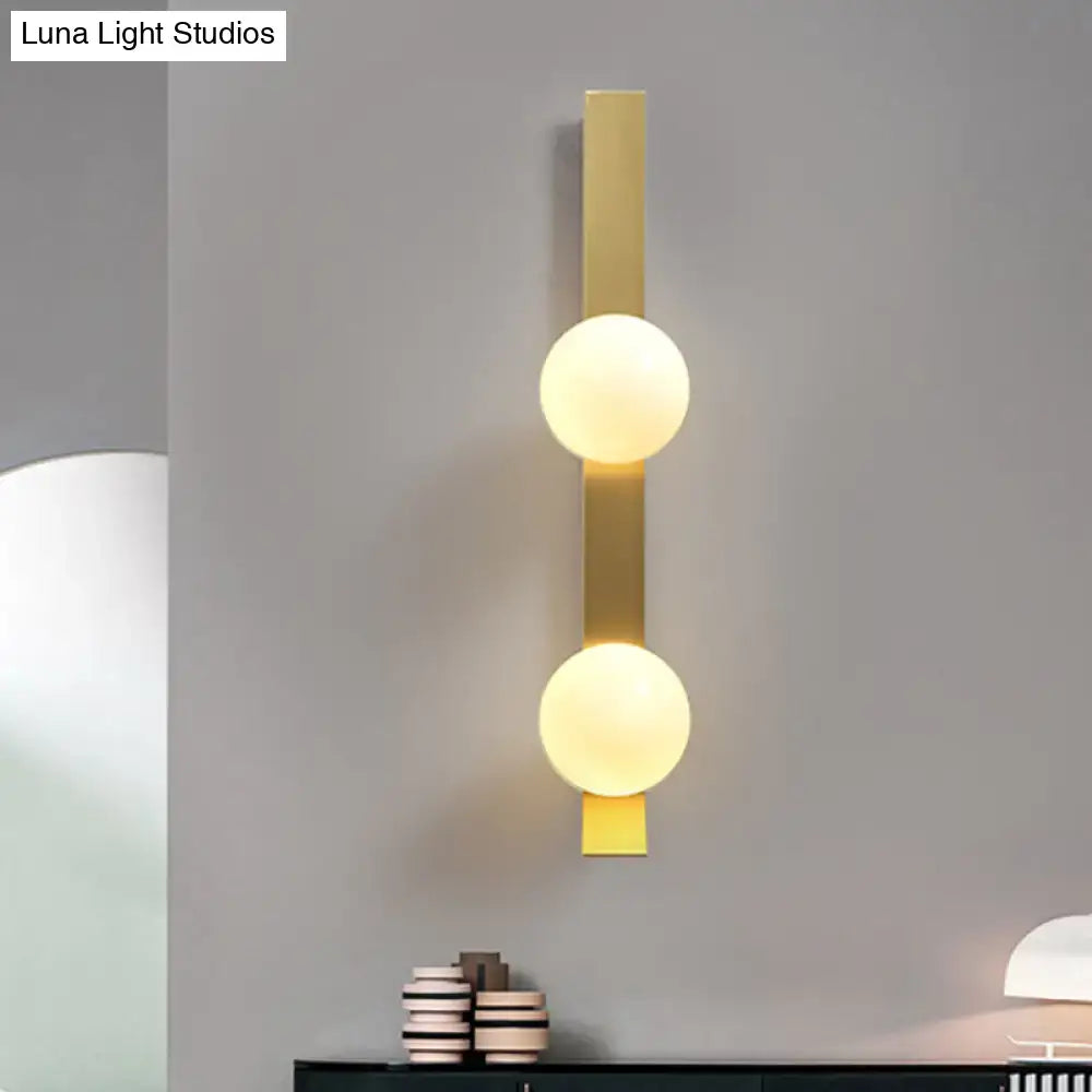 Vintage brass wall light with gold-toned metal and two softly glowing ivory glass shades for bedroom sconce lighting