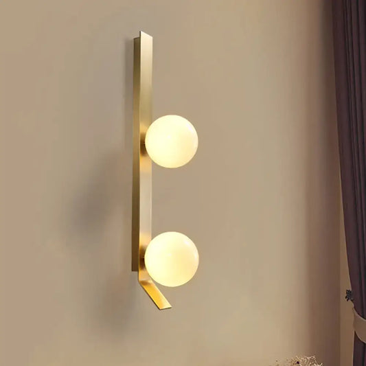 Vintage brass wall light with gold-toned metal bar and ivory glass shade featuring two spherical frosted globes