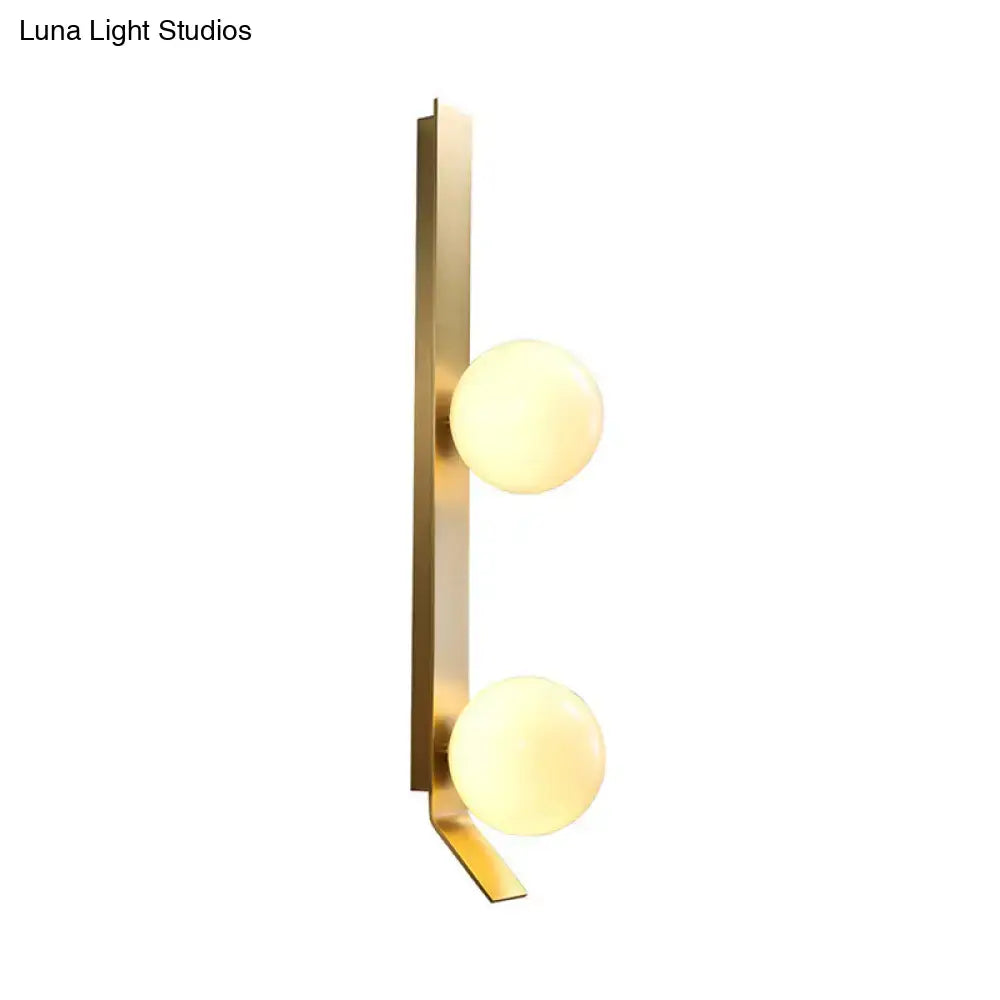 Modern brass wall light with ivory glass shade featuring two warm-toned spherical globes for bedroom use