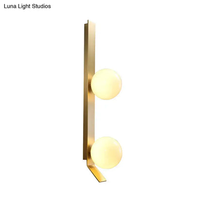Modern brass wall light with ivory glass shade featuring two warm-toned spherical globes for bedroom use