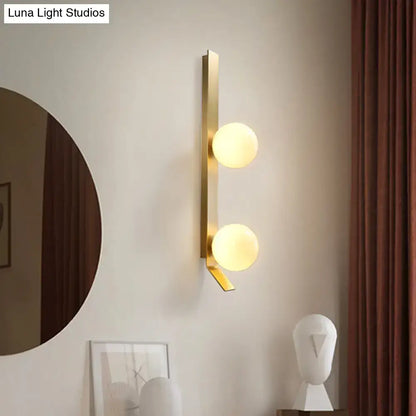 Modern gold-toned wall light with two ivory glass shade spheres ideal as a vintage brass bedroom sconce