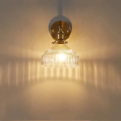 Vintage brass wall lamp with ribbed glass pull chain shade diffusing warm light for living room use