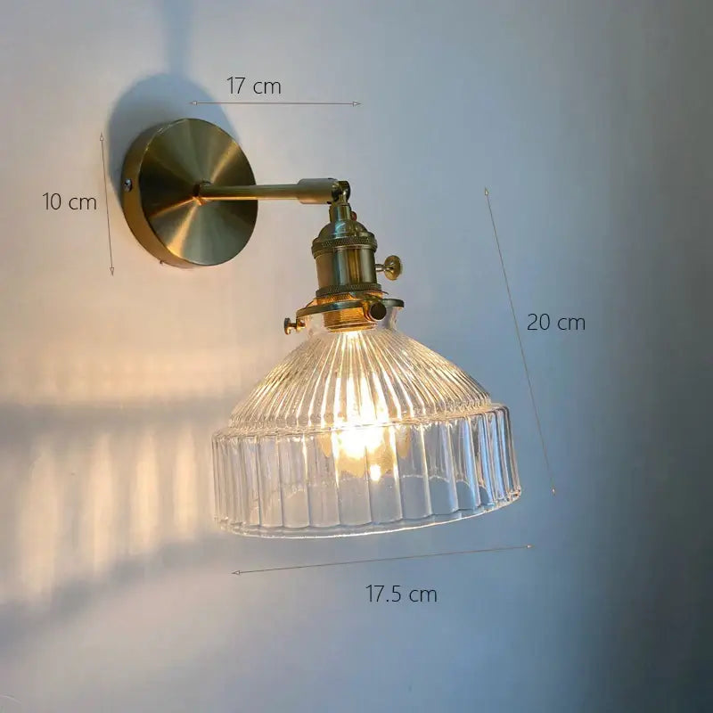 Vintage brass wall sconce with clear ribbed glass shade designed as a bedroom wall lamp