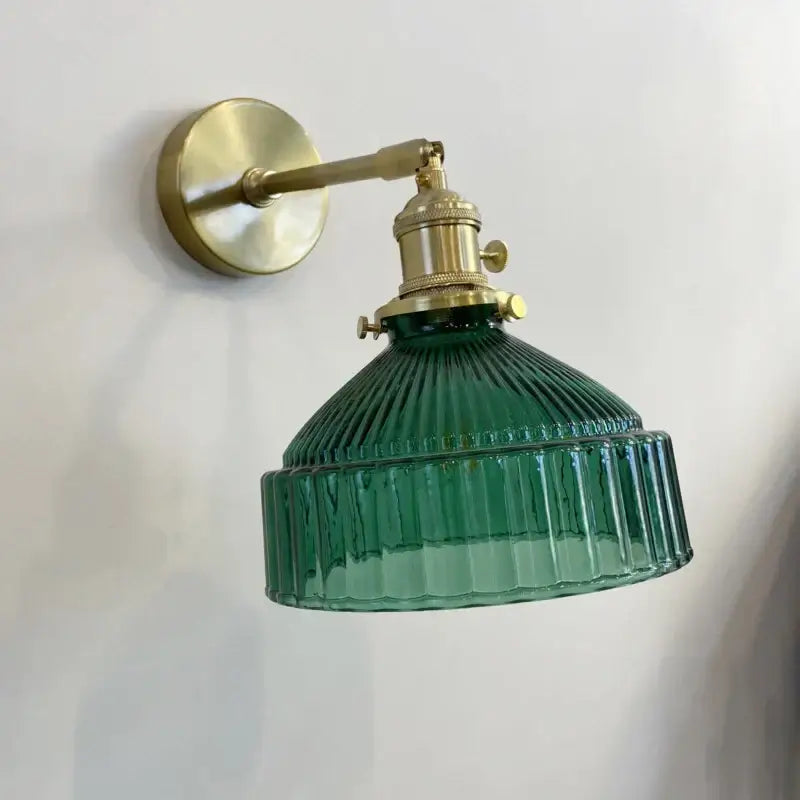 Vintage wall sconce with green ribbed glass shade and brass hardware perfect as a bedroom wall lamp
