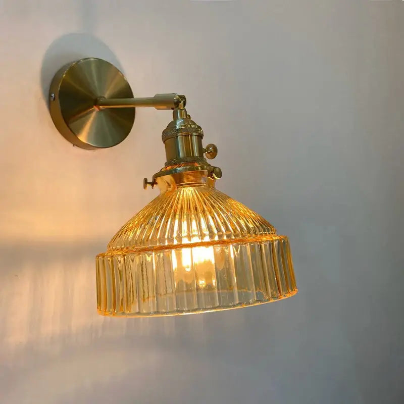Vintage brass wall sconce with amber ribbed glass shade and metal arm for elegant bedroom wall lamp lighting