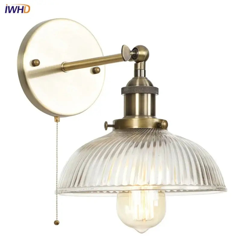 Vintage brass wall sconce with ribbed glass shade and exposed filament bulb featuring a pull chain switch