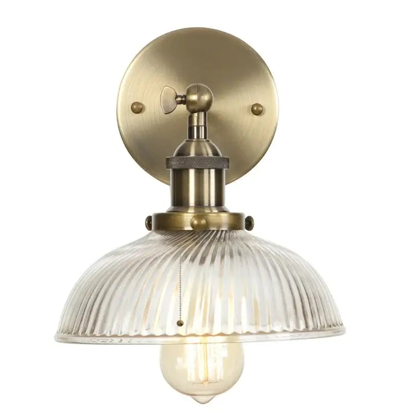 Vintage brass wall sconce with ribbed glass shade and exposed filament bulb featuring pull chain switch for bedroom light