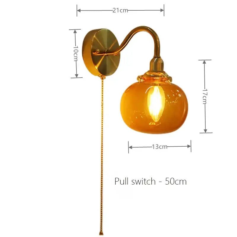 Vintage brass wall sconce lamp with rounded amber ribbed glass shade and pull chain switch for bedroom use