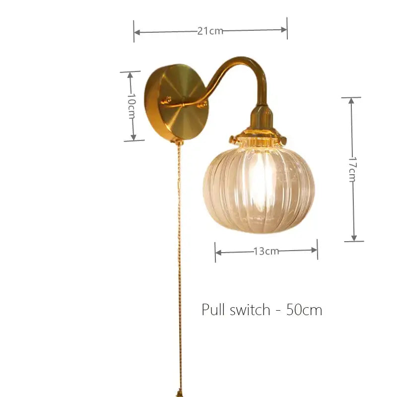 Vintage brass wall sconce lamp with gold-toned curved arm and ribbed translucent glass globe for bedroom use