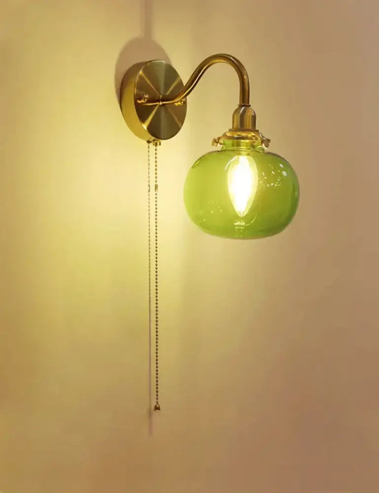 Vintage brass wall sconce lamp with ribbed translucent green glass globe and pull chain switch for bedroom use
