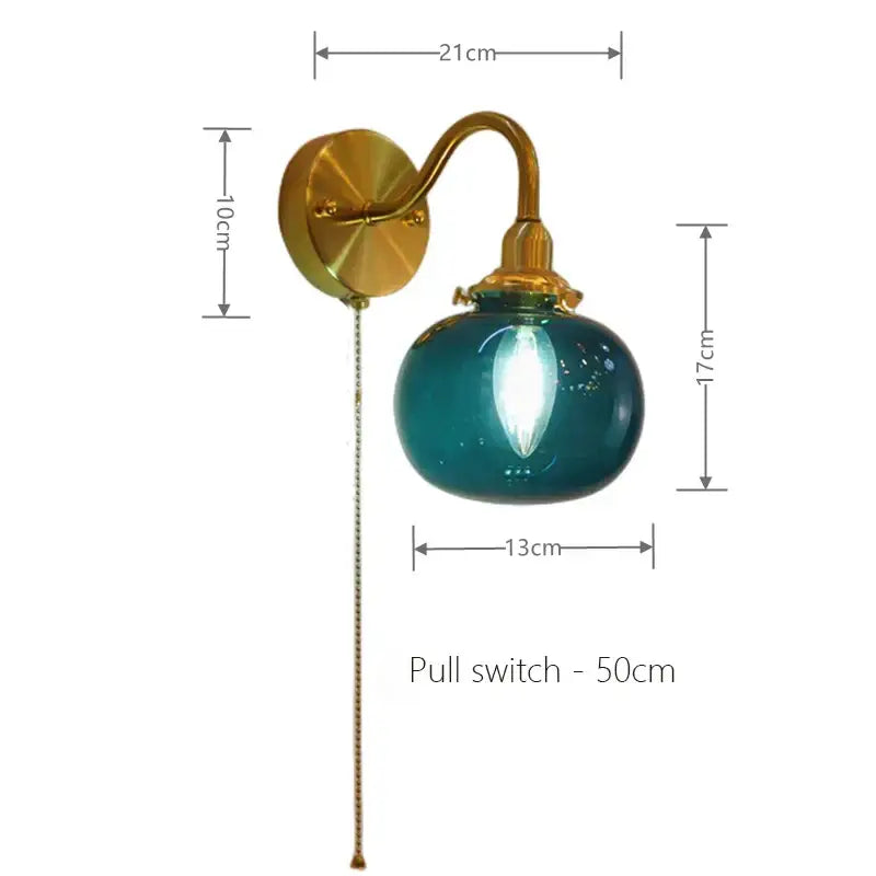 Teal glass globe wall sconce lamp with vintage brass ribbed hardware and pull chain switch for bedroom lighting