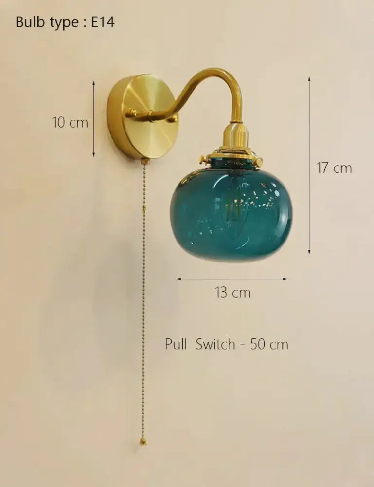 Teal glass globe wall sconce lamp with vintage brass ribbed metal arm and pull chain switch for bedroom lighting