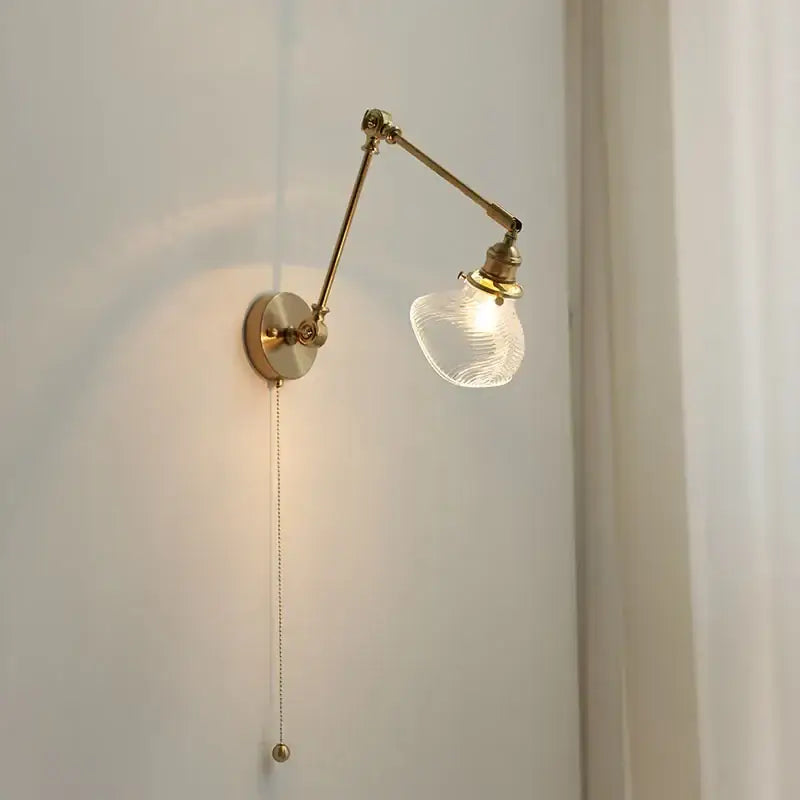 Vintage brass swing arm wall light fixture with adjustable brass finish and textured glass shade for bedroom use