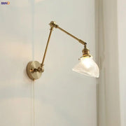Vintage brass swing arm wall light fixture with adjustable brass finish and textured translucent glass shade for bedroom use