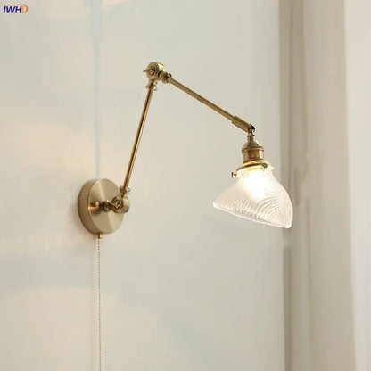 Vintage brass swing arm wall light fixture with adjustable brass finish and textured translucent glass shade for bedroom use