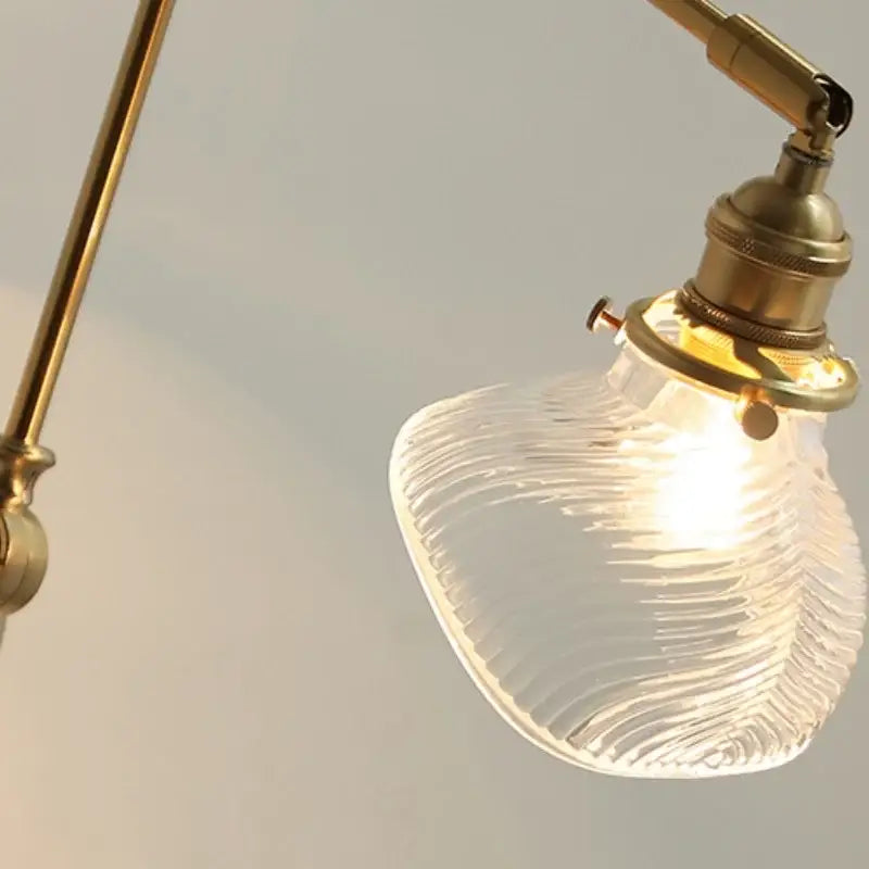 A warm-glowing vintage brass wall light fixture with a clear ribbed glass shade for bedroom sconce use