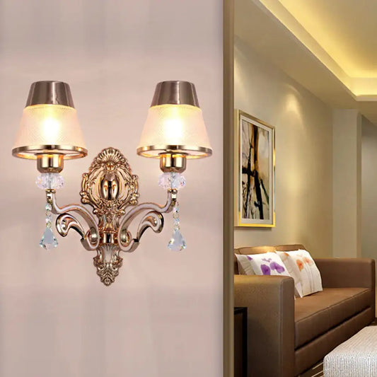 Antique brass two-light wall lamp with cream fabric shades and crystal droplets featuring clear glass shade design